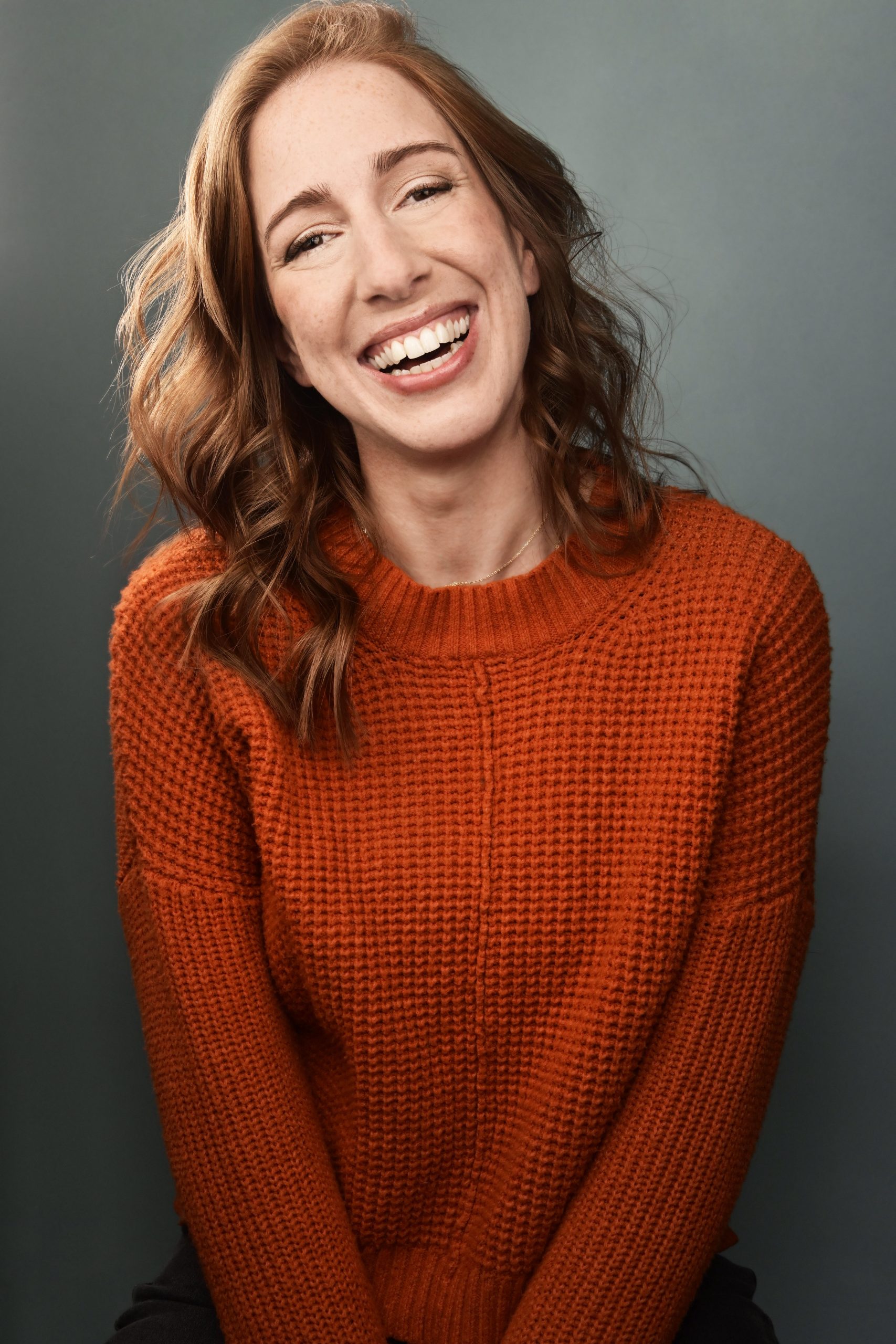Rachel Wright Headshot Orange Sweater Grey Background
